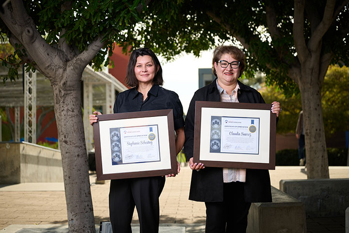 Two people holding up framed awards