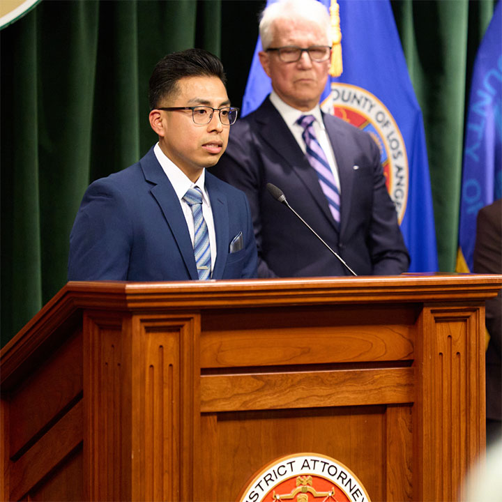 A person in professional attire standing at a podium speaking into a microphone